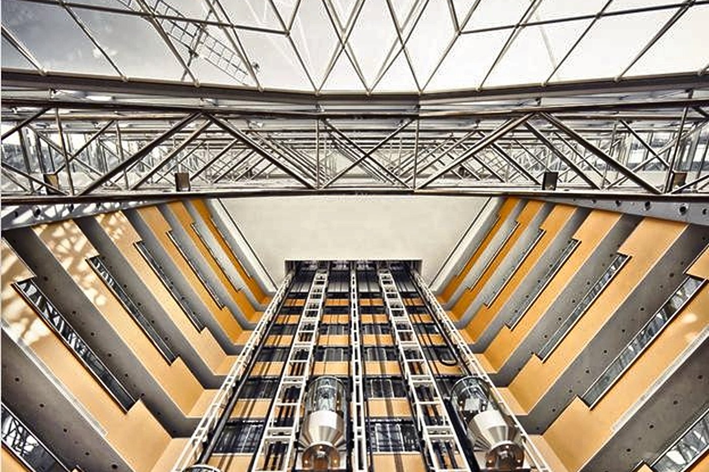 Lif panorama berkaca menaik melalui atrium bercahaya semula jadi